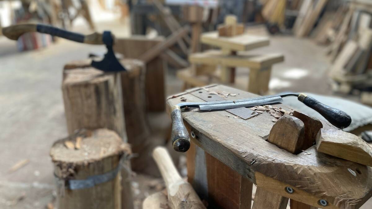 A hand-built reciprocating springpole lathe is nestled on the traditional end of the workshop, using ropes and a treadle for turning wood, while other antique tools find home.