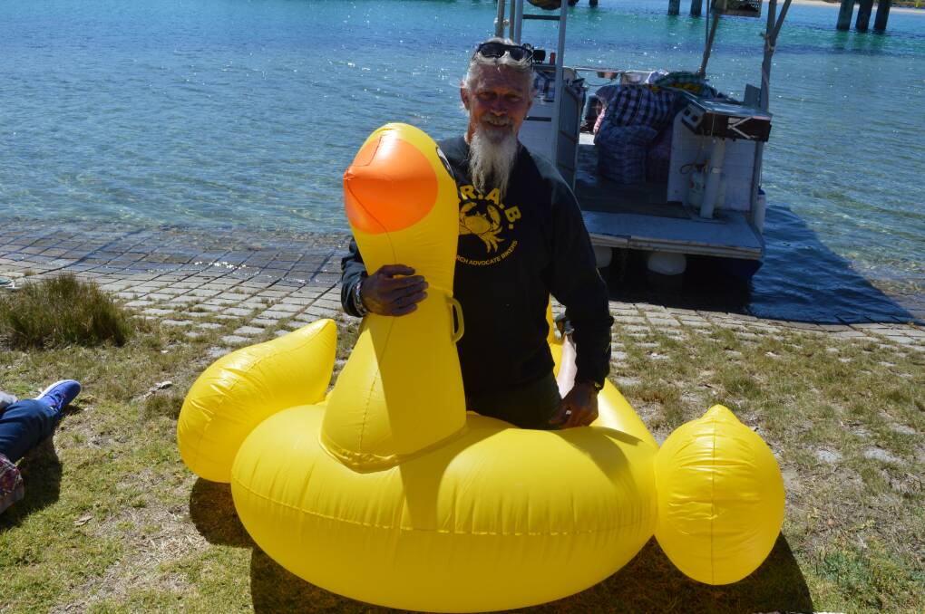 National president of CRABs Rob Grimstone of Bermagui on one of the 20 giant ducks that raced across the Bermagui River before 1000 plastic ducks were released.