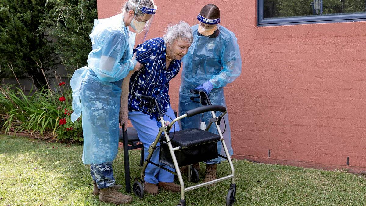 Royal Australian Air Force medics Corporal Amy Hutchison (left) and Aircraftwoman Laura Millen assist aged-care resident Gwen Metcalf at an aged-care facility in Tura Beach. Photo: Defence