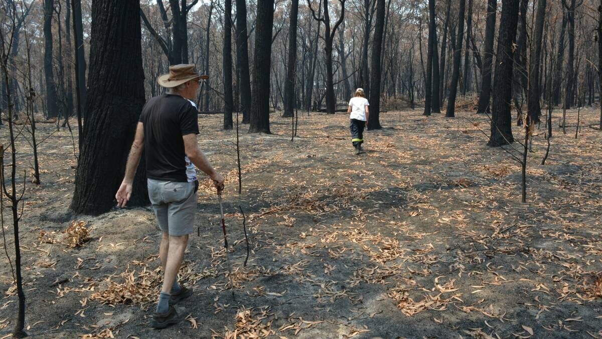 Paul Whitington and partner Kerri-Lee Harris wander through their burnt Wonboyn property. Photo: Ben Smyth
