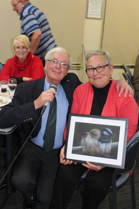 Andrew Ogilvie, quizmaster, with Diana Winter and the artwork she donated to the Friends of the Old Bega Hospital Trivia Night auction.