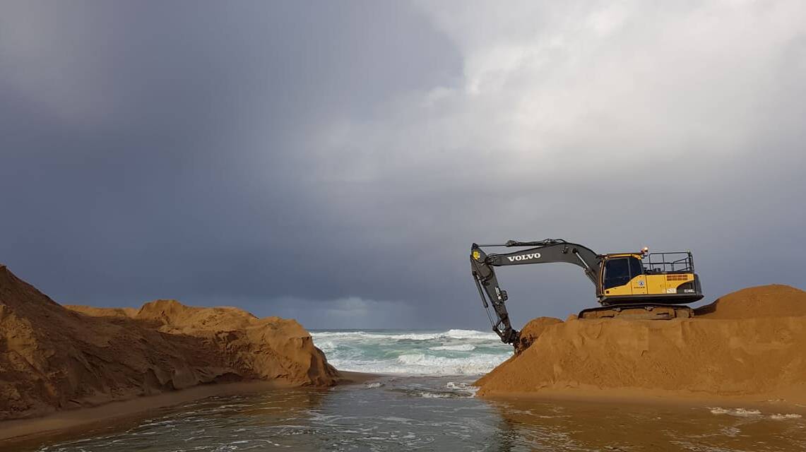 Workers open the Bega River mouth at Mogareeka on Tuesday as rain drenches the district. Picture: Cliff Shipton