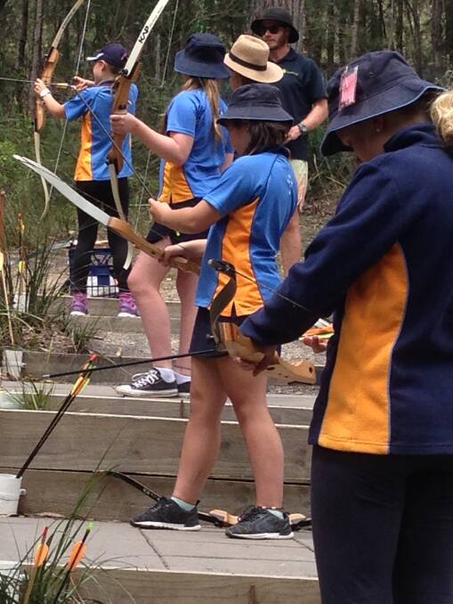 Bega and Merimbula Girl Guides try archery at Kianinny Cabins as part of their annual district Guide camp.