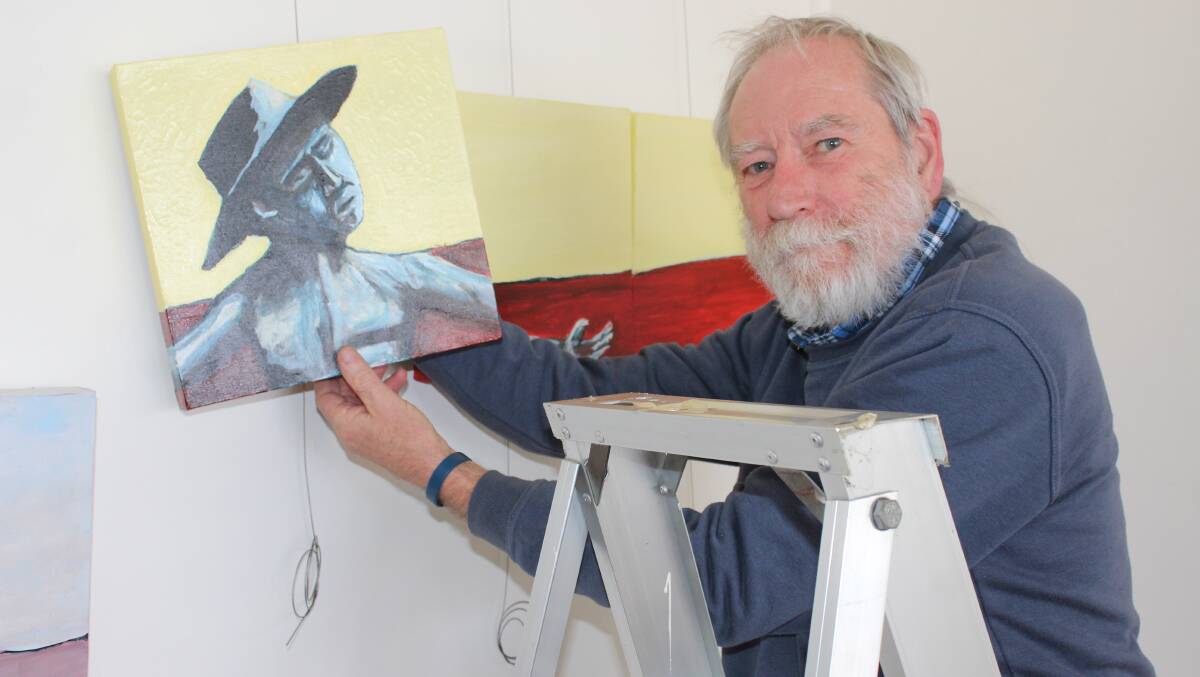 LESSON IN ART: Former Bega High School teacher Steve Stafford helps hang artworks at Spiral Gallery for its latest exhibition, featuring work of past and present high school staff. Photo: Ben Smyth