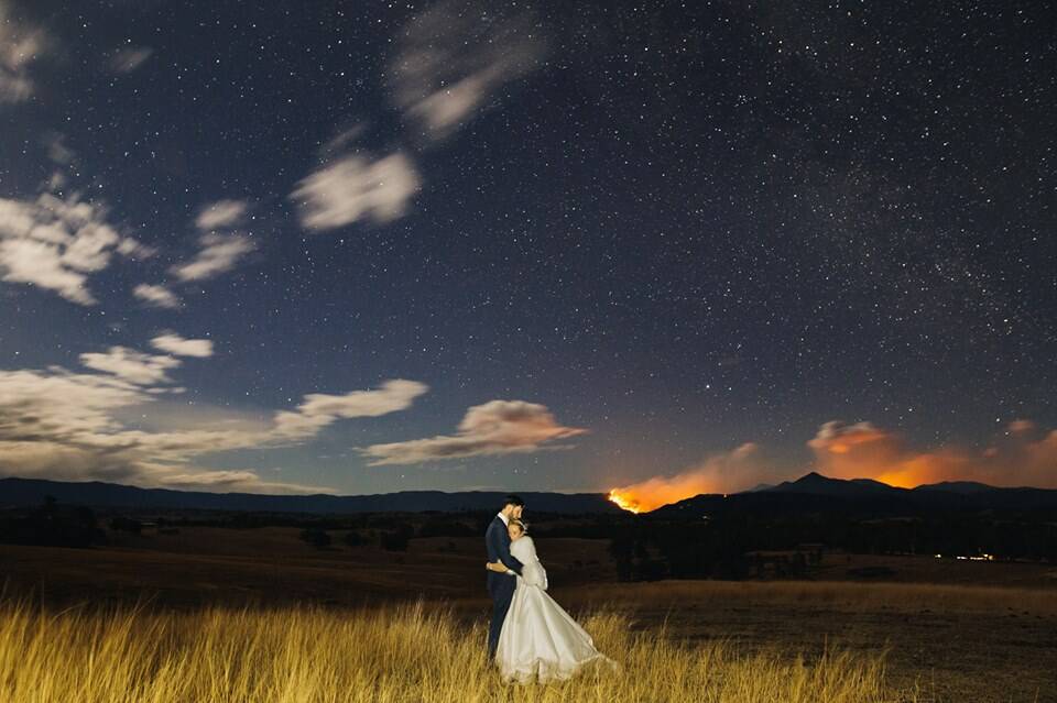 Annie Gard and Theo Small are married on family property at Kameruka as the Bemboka fire burns in the distance. Picture: Jack Chauvel Photography