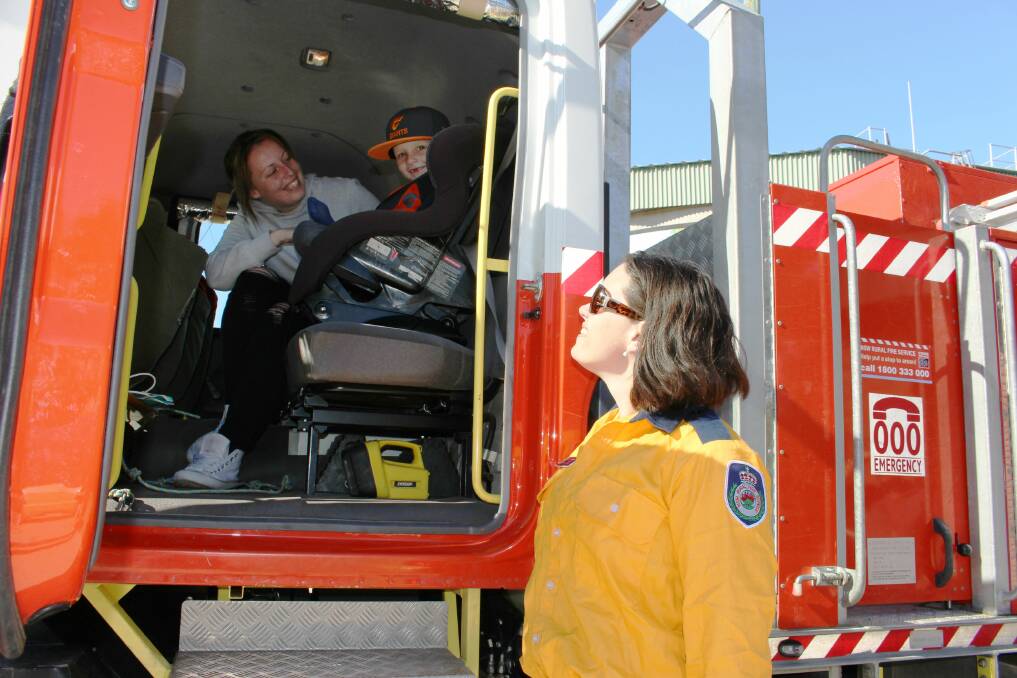All aboard the big red fire truck! Mother Hannah White fastens Joshua's seatbelt as RFS volunteer Sam McGovern gets ready to roll out. 