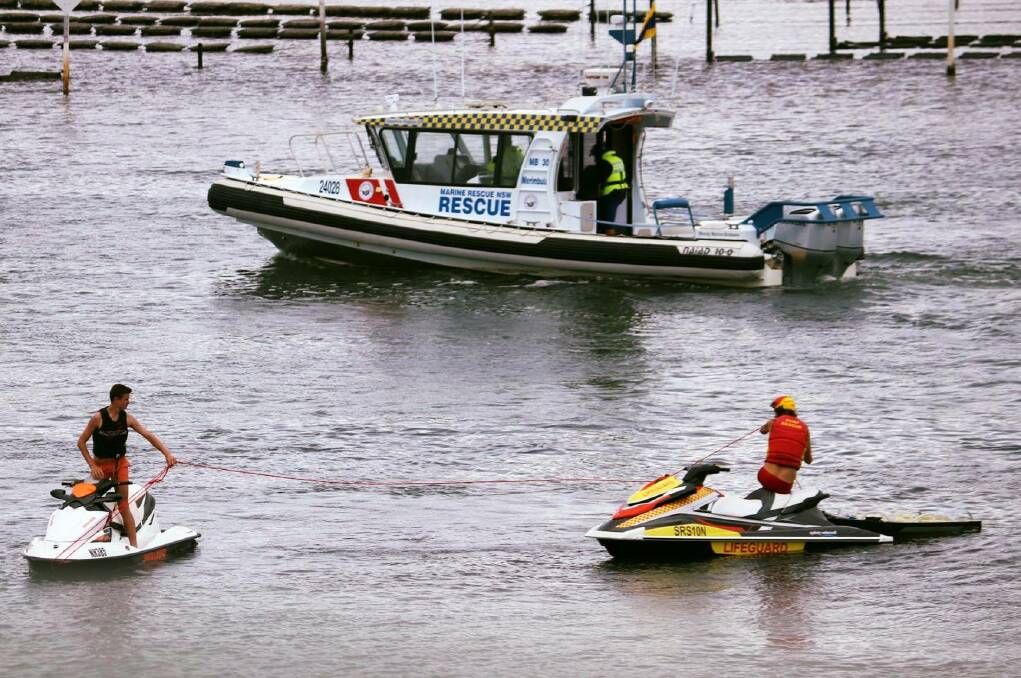 Merimbula Marine Rescue hand over to the lifeguard who tows the broken PWC safely under the bridge to the boat ramp. Picture: Supplied.
