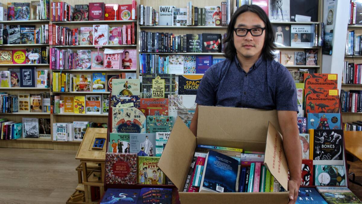 NOVEL IDEA: Myoung Jae Yi of Candelo Books holds one of the boxes of donated paperbacks available to fire-affected Tathra residents. Photo: Alana Beitz 