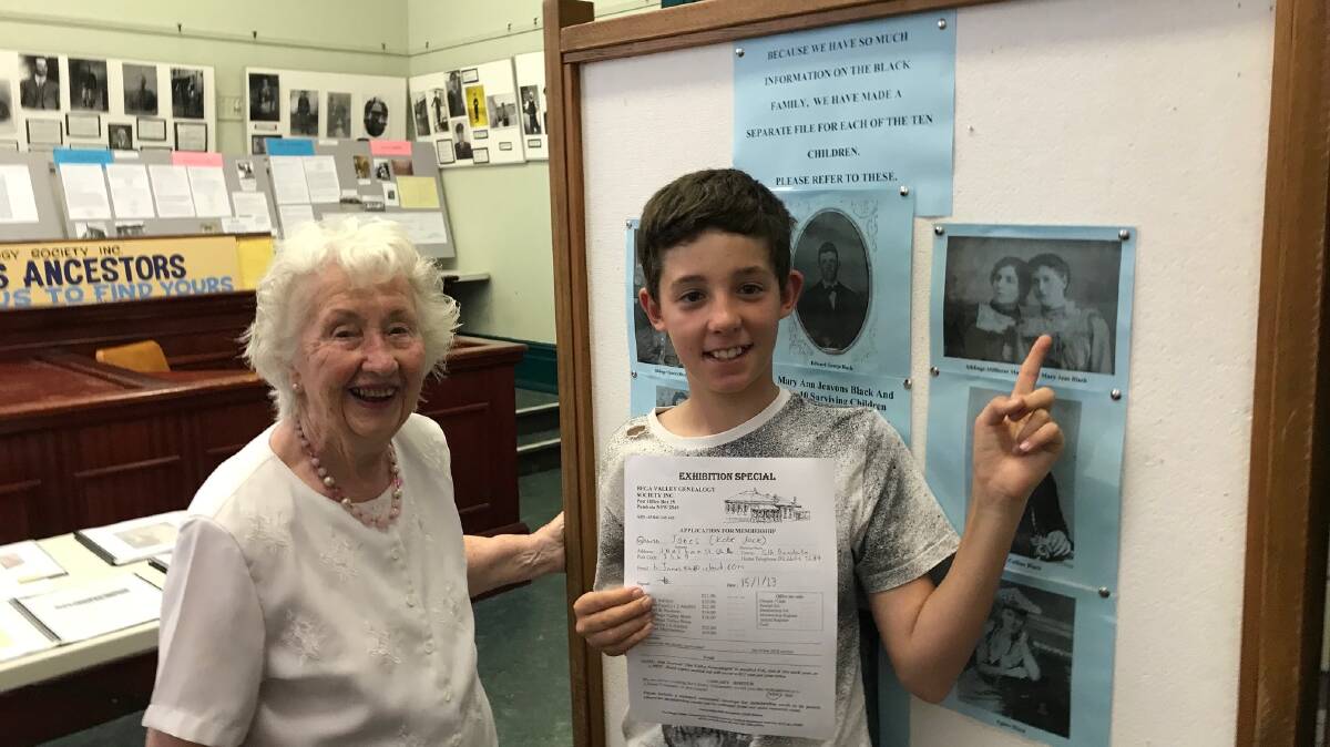 Bega Valley Genealogy Society librarian Ursula Hunt and Kobe Jones, pointing to a photo of his great great grandmother and holding his complimentary membership to the society.