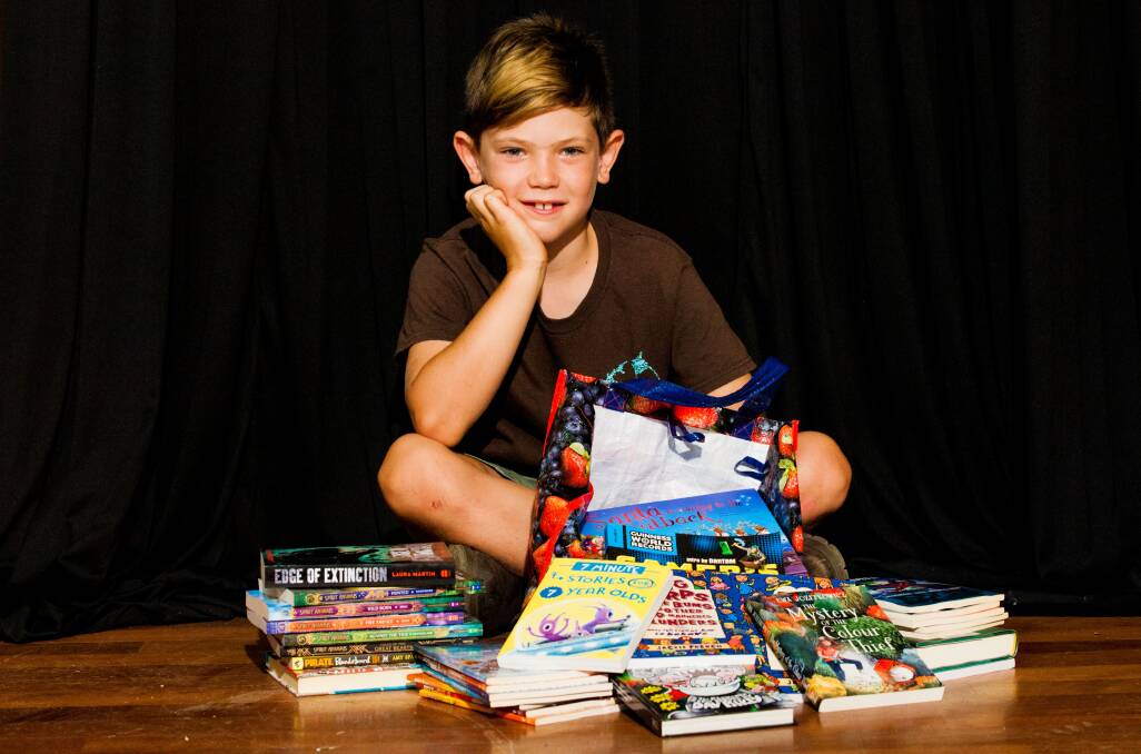 AVID READER: Malakai Nave, 8, lost all of his beloved books in the Tathra bushfire. On Saturday he was ecstatic with donations to refill his bookshelf. Pictures: Rachel Mounsey