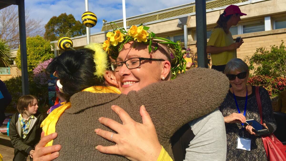 We are with you: A hug of support after Bega woman Arwyn Hankinson's hair was shaved off in an emotional school assembly for Daffodil Day.