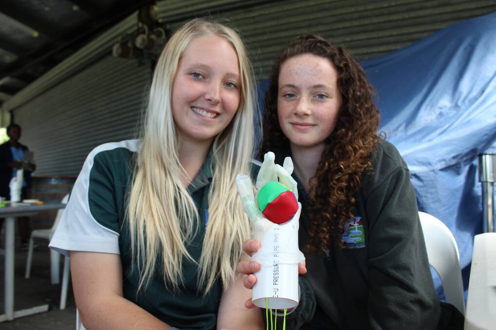 Shanice Hepburn and Lila Moore of Year 10 at Sapphire Coast Anglican College hold a bionic hand they built. 