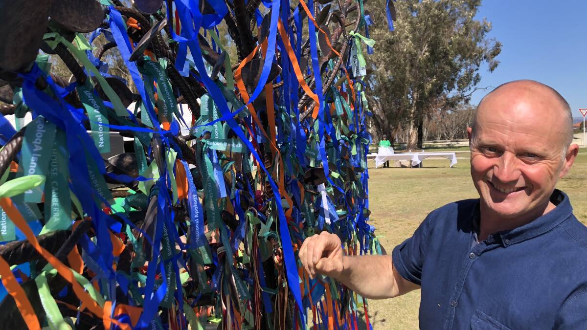 Richard Moffatt hangs a ribbon onto his sculpture for his father. 