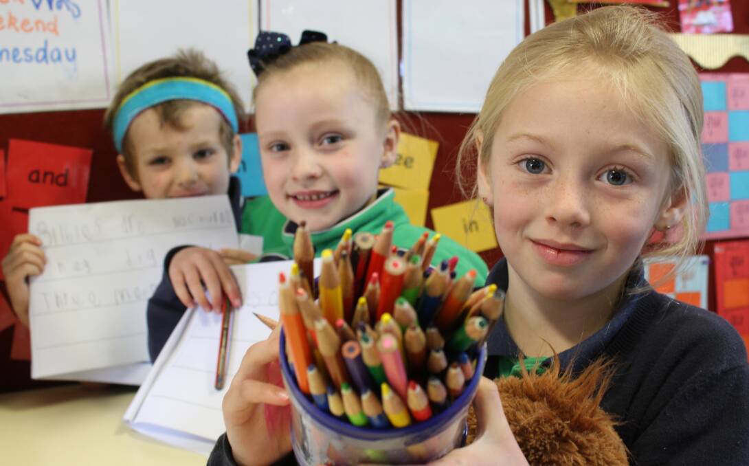 Kindergarten pupils Leo, Freya and Maharleya enjoy drawing and writing in class at Bega Valley Public School. 