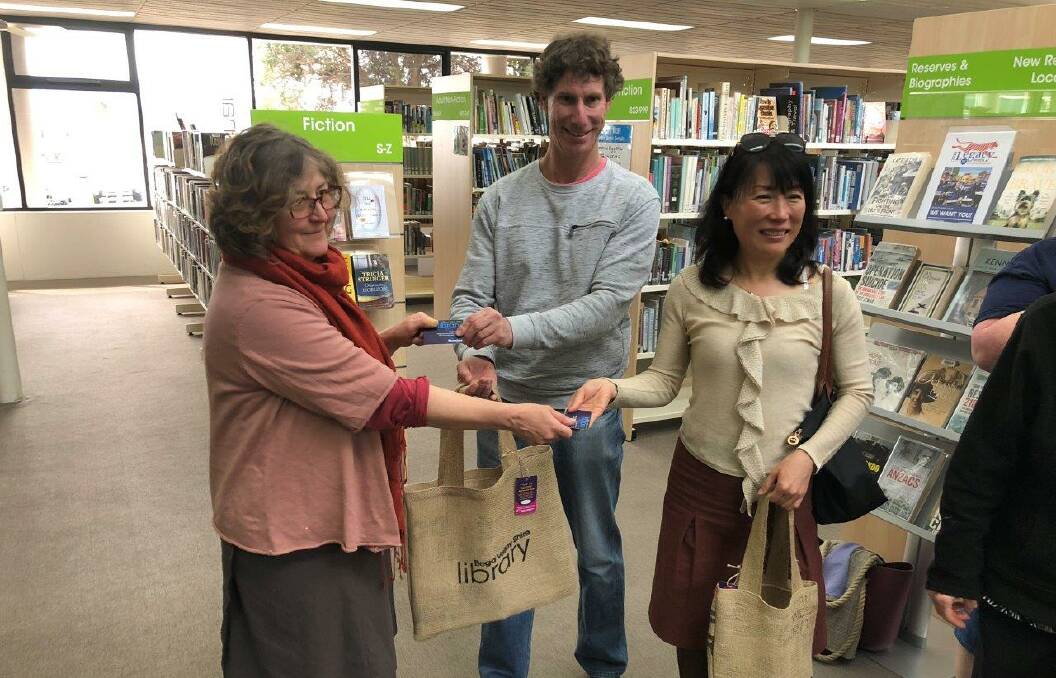 Systems librarian Megan Jordan-Jones takes delight in handing over a library bag to two new members of the library. 