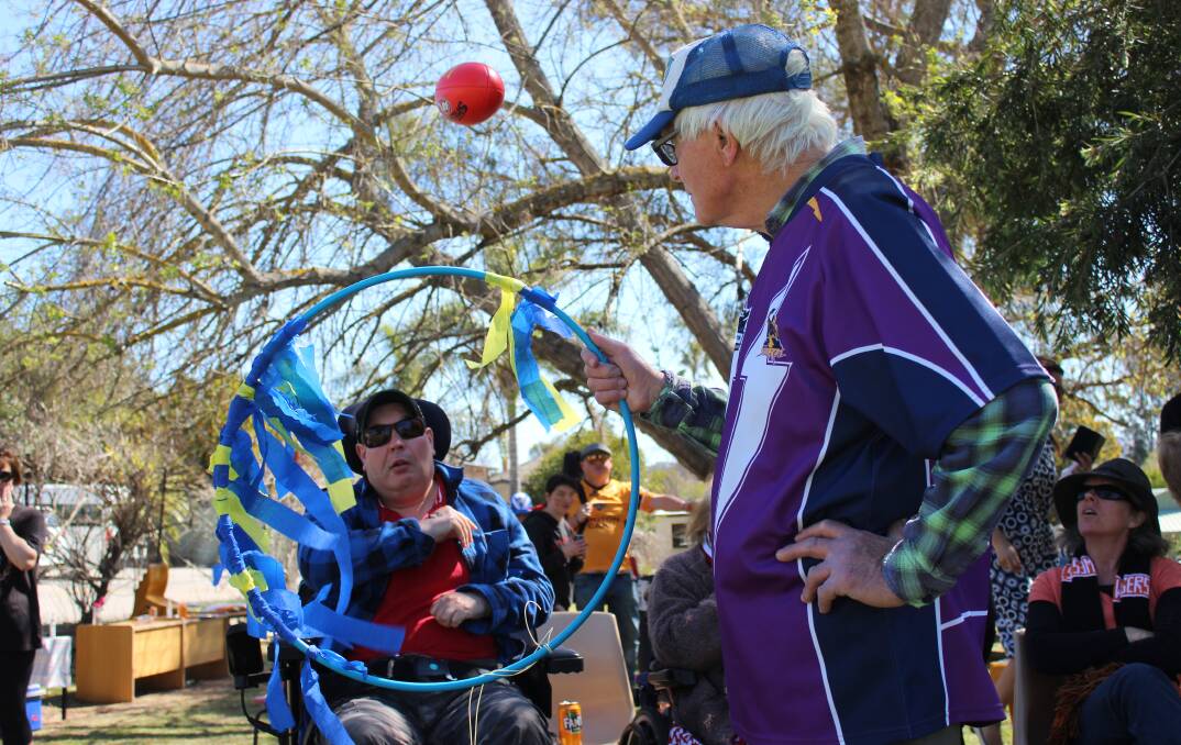 Graham Henkle throws a football at a hoop held by Wayne Raymus. 