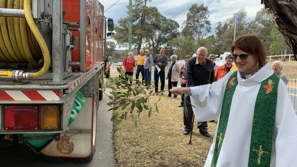 Rev Lou Oakes gives thanks to and blesses the Wolumla RFS crews and their fire trucks. Behind her is Bobby Anderson, who has over 50 years service with the Wolumla RFS.