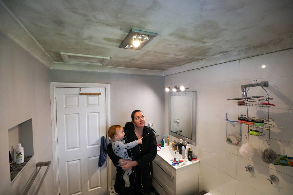 HEALTH HAZARD: Renee Ellington with her son son Greyson, 1, in the bathroom of their previous rental home in Albion Park, where black mould occupied many ceilings and walls. After battling her landlord to fix the issue she was finally able to break the lease and move out. Picture: Adam McLean