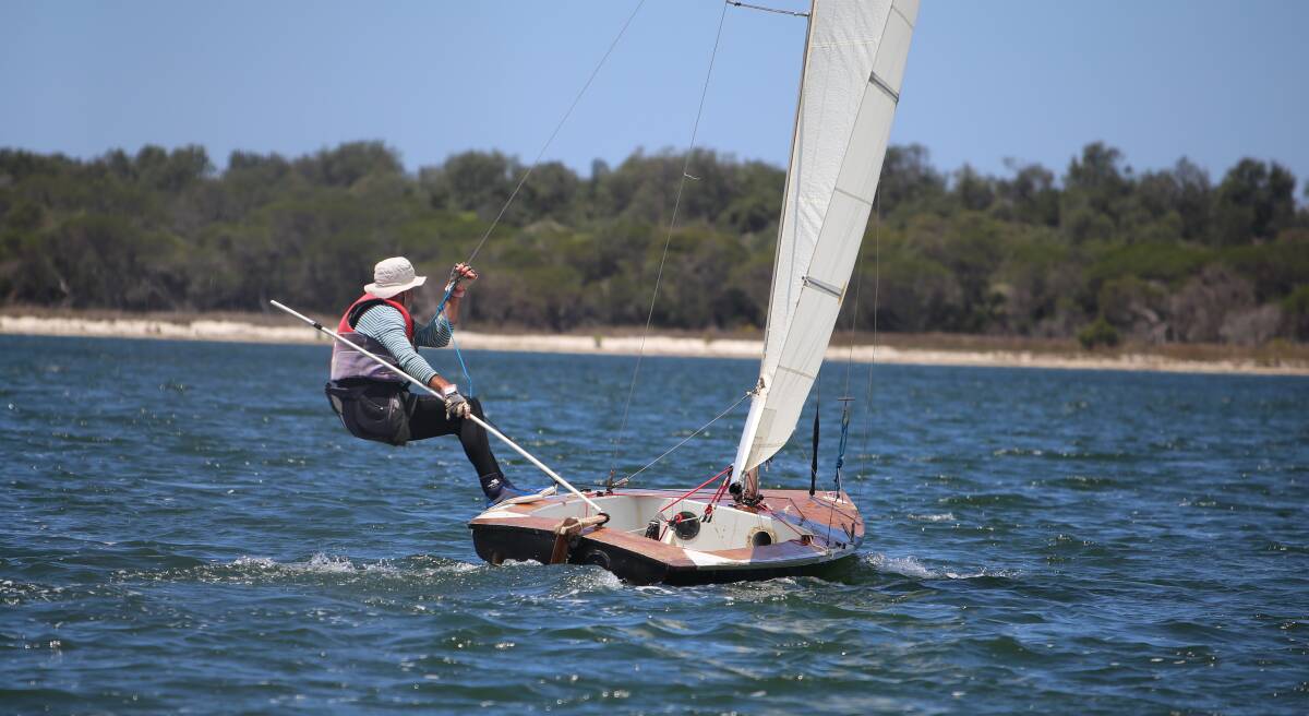 Out of boat experience: A sailor counter-balances the wind during a Wallagoot race with club members competing in the Jindabyne regatta. 