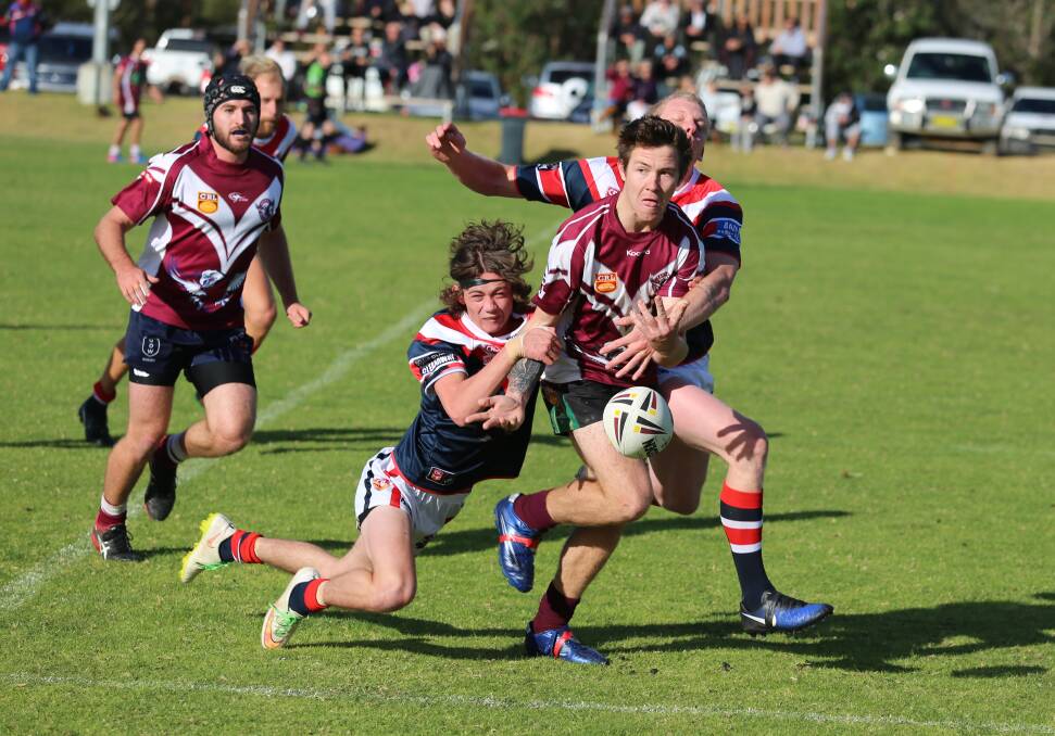 Offload: A Tathra player gets the offload out during a tackle attempt by two Bega Roosters defenders in a closely-fought derby on Sunday. 
