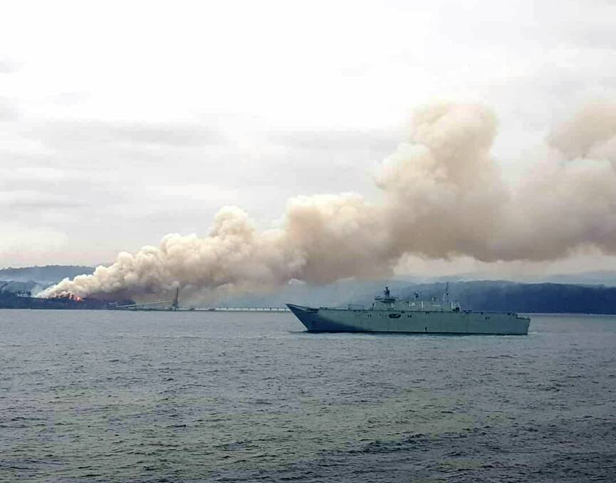 Painful loss: Smoke is seen pouring from the chip mill on Monday morning with HMAS Adelaide in Twofold Bay. Picture: Melina Caldwell. 