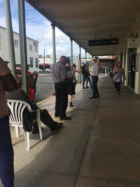 A long line outside Bega's Centrelink office on Tuesday includes one man who used a borrowed a chair from a gallery next door. Picture: Rebecca Lamont