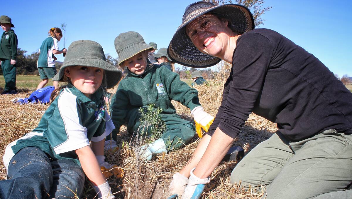 PLANTING: Makayla Fulton and Patience Dowd with Bega River and Wetlands Landcare community coordinator Erin Moon on Friday.