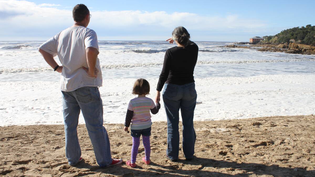 Jamie Forbes, Stella Forbes and Becky Lupton watch the large swell roll in off Tathra Beach on Tuesday morning.