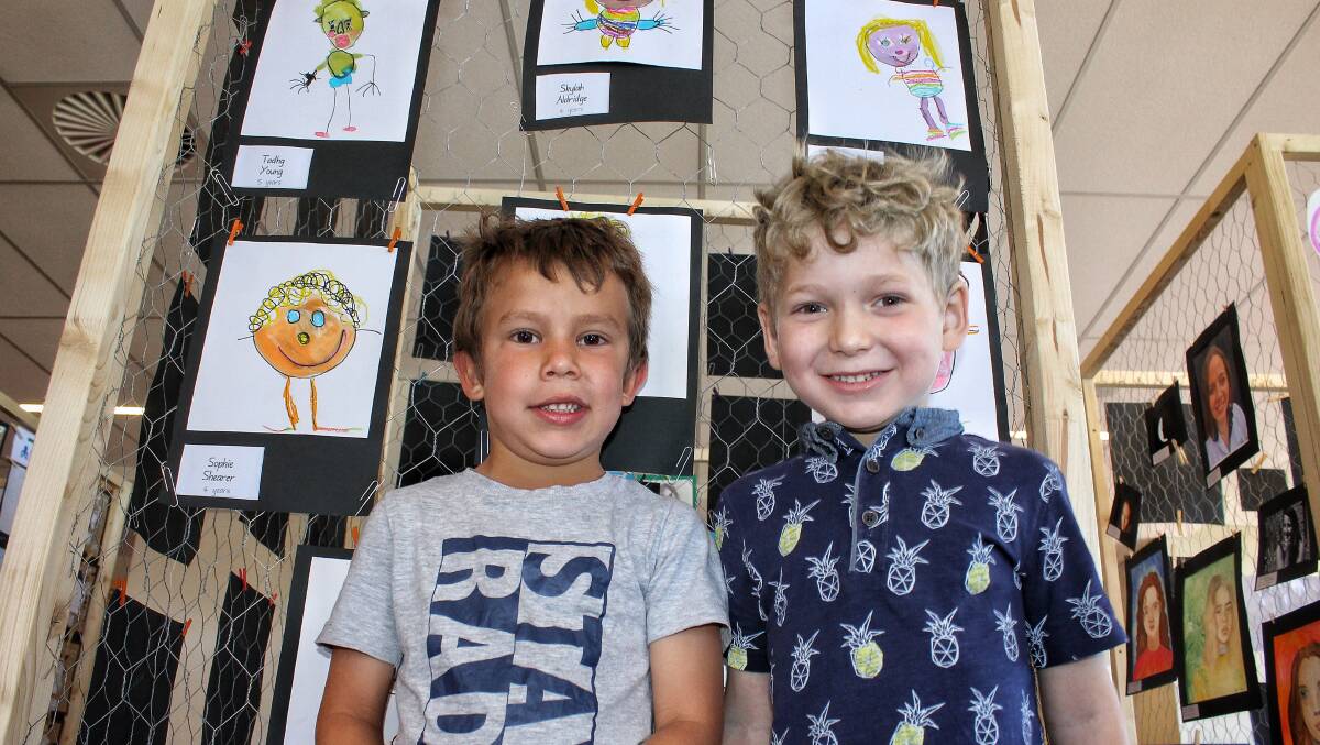 SMILES: Bega Preschool's Kayleb Vincent-Pobjie and Conor Herbert-Scott stand next to portraits for this year's Festival of the Face at the Bega civic centre on Monday. Picture: Alasdair McDonald
