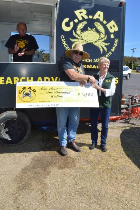 CRABs duck race organiser Jim Gilchrist presents a cheque for $5000 to Lori Hammerton of Bega Valley CanAssist following Sunday's duck races in Bermagui.