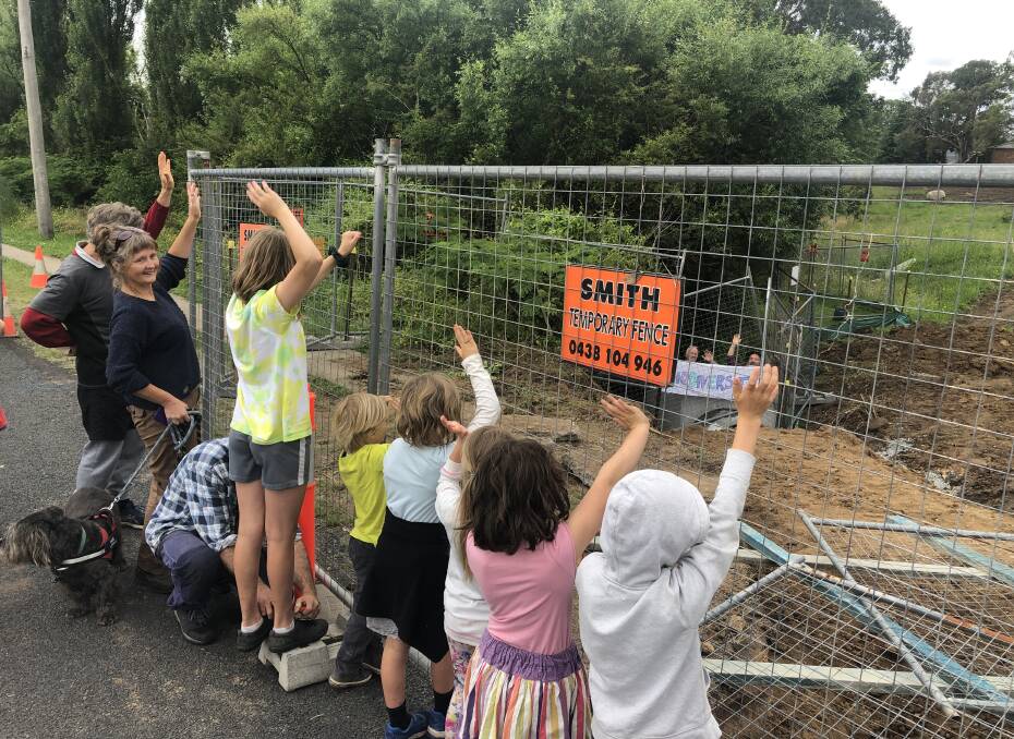 Friends of the Glebe Wetlands members and onlookers wave to the two activists from behind the construction site fencing. Photo: Leah Szanto