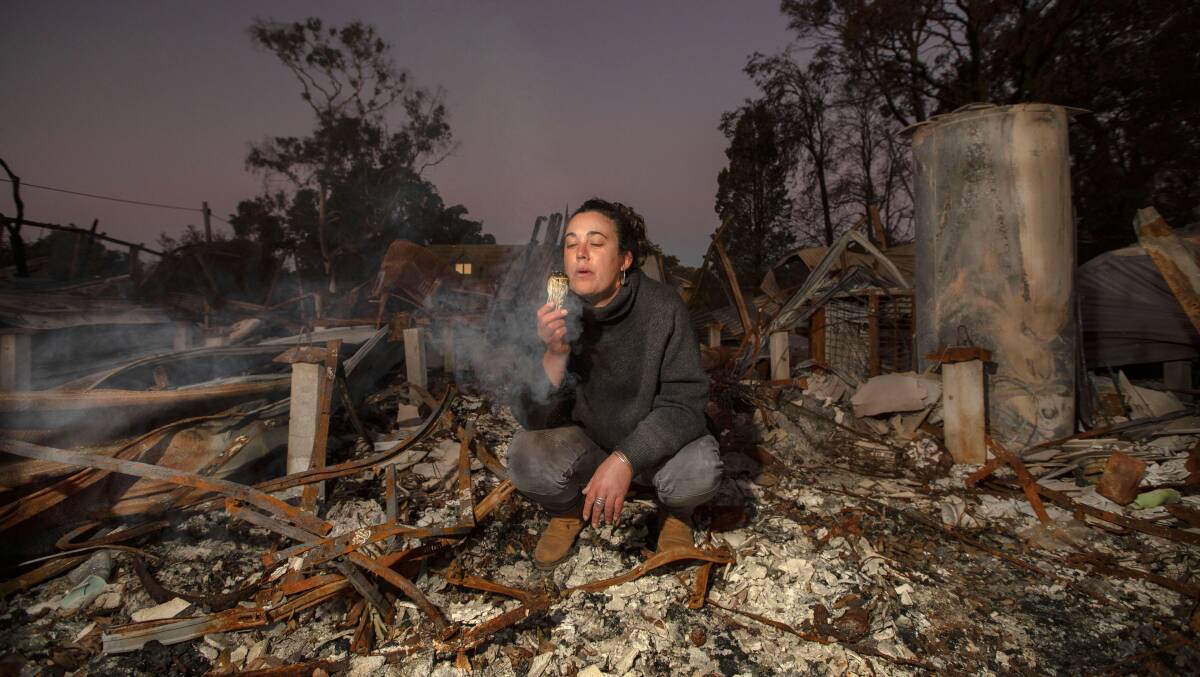 Mallacoota resident Jess van Swoll crouches in the ashes of her burnt out home. Photo Rachel Mounsey
