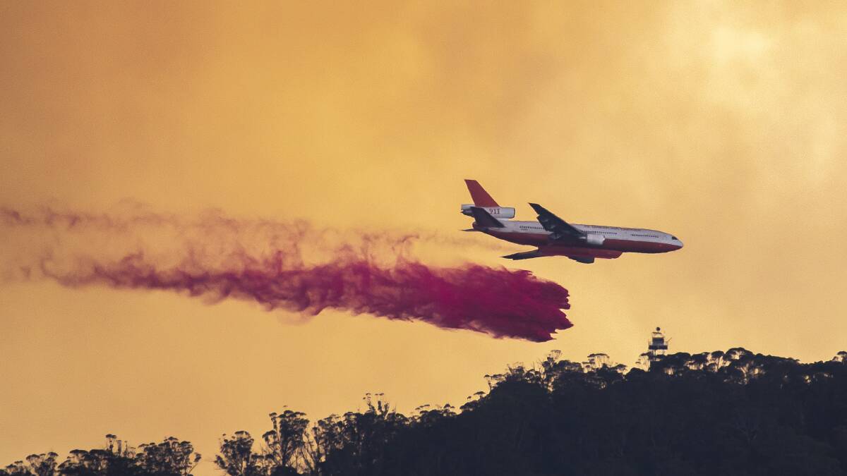 An aircraft drops fire retardant on Mt Tennant on Tuesday afternoon. Picture: Sitthixay Ditthavong