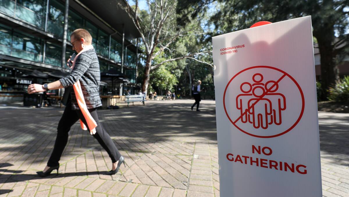 University of Wollongong student walking past a no gathering sign. Picture: Adam McLean.