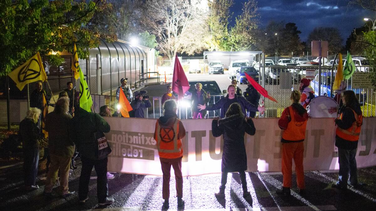 Extinction Rebellion members prevent Comcar vehicles from leaving their Fyshwick compound early Tuesday morning. Picture: Sitthixay Ditthavong