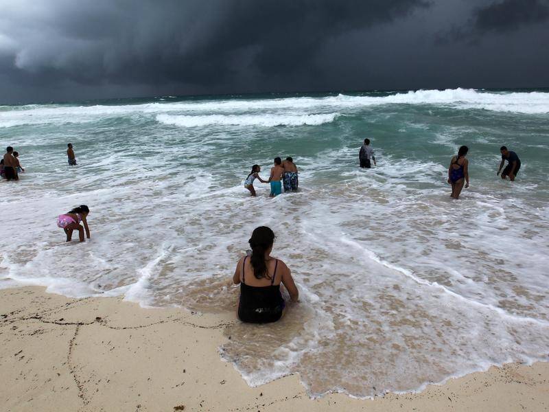 People swim in the turbulent sea in Mexico as Hurricane Michael approaches.