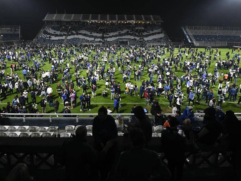 Gimnasia la Plata fans flood the field after Argentine police fired tear gas outside the stadium. (AP PHOTO)