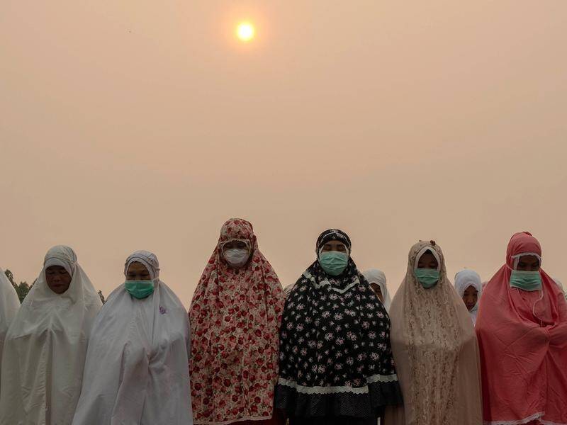 Indonesian women wear protective masks as they pray for rain to combat the haze and drought season.