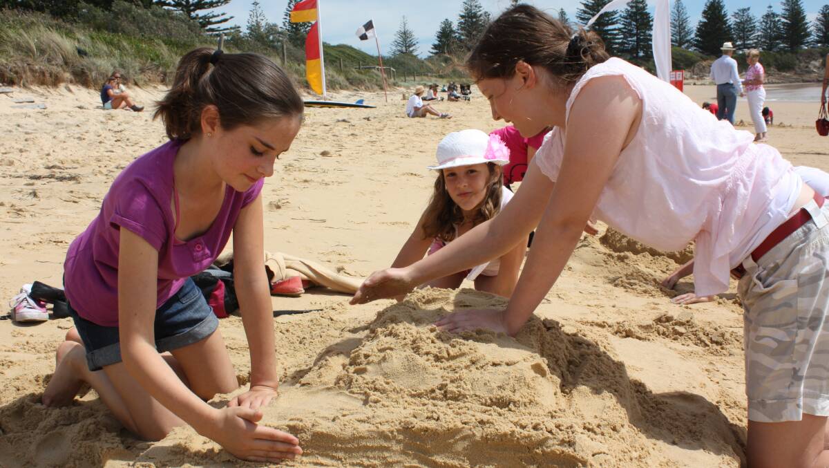 Bermagui’s Olivia Buchli and Hannah Buchli, and Hannah Klurt of Cobargo shape their entry during last year’s Bermagui Seaside Fair sandcastle competition. 
