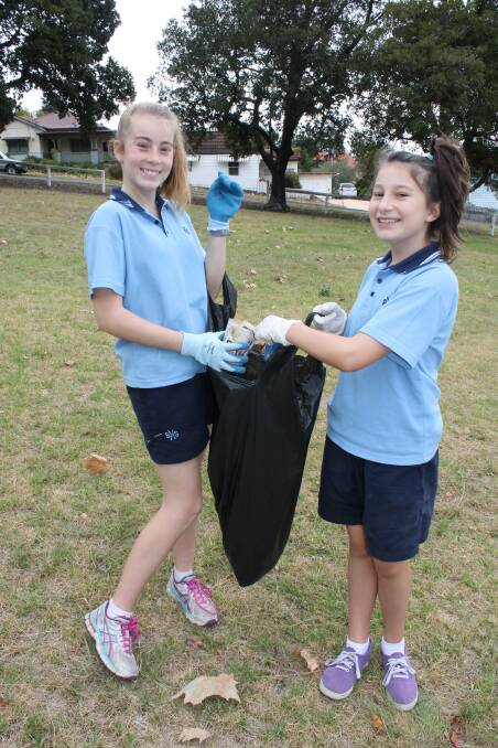 Simone Blacka and Lexi Underhill pick up rubbish in Bega Park.