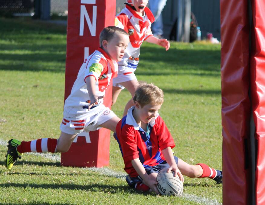 Aiden Reeves gets the better of two Tuggeranong Dragons defenders to plant a try for the Bega Roosters under 7s on Saturday morning. 