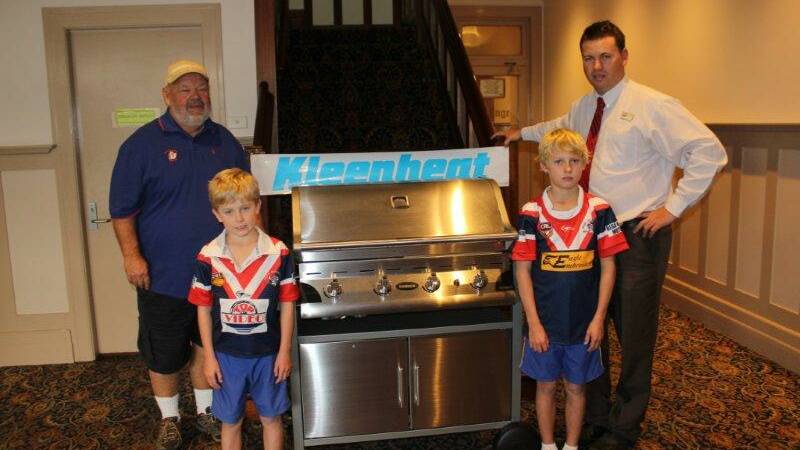 • Kevin Hinton (left) from Glen Mia Gas donates a barbecue for the Bega Minor Rugby League Football Club raffle to club president Norm Griffin with eager players (front) Liam and Jasper Kelly. 