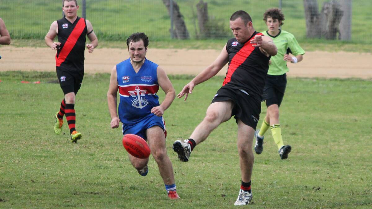 • Bomber John “Moona” Harney (right) kicks to a team-mate, while his Digger opponent charges for the ball on Saturday. 