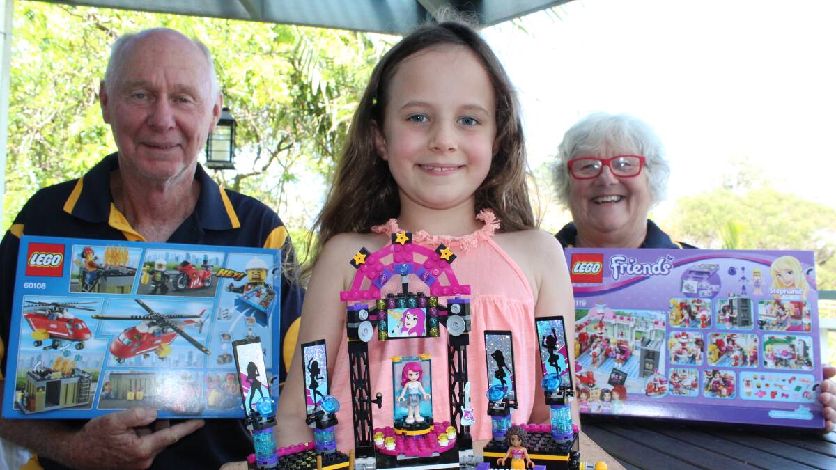 LEGO FANS: Pambula Rotarians Steve Goodchild and Lee Beatty with seven-year-old Scarlette Culliver who is holding an impressive display she built. Picture: Mel Leach