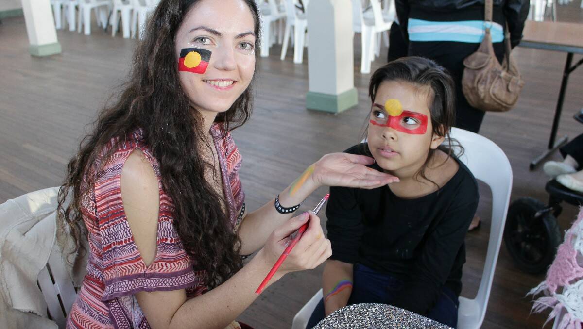  Lisa Heffernan (left) paints an Aboriginal flag on Linia Aldridge's face at Bega's NAIDOC Week celebrations today.
