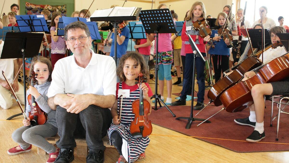 South Coast Music Camp director Geoffrey Badger catches up with Josephine Roumanoff, 5, and Imogen Bichard, 7, as the band plays on.
